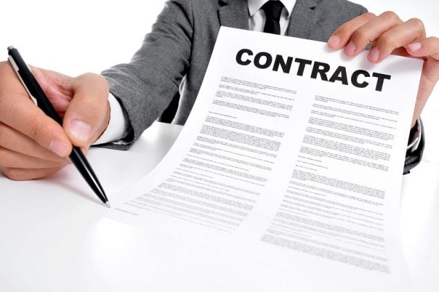 man wearing a suit sitting in a table showing a contract and whe | The Outerhaven