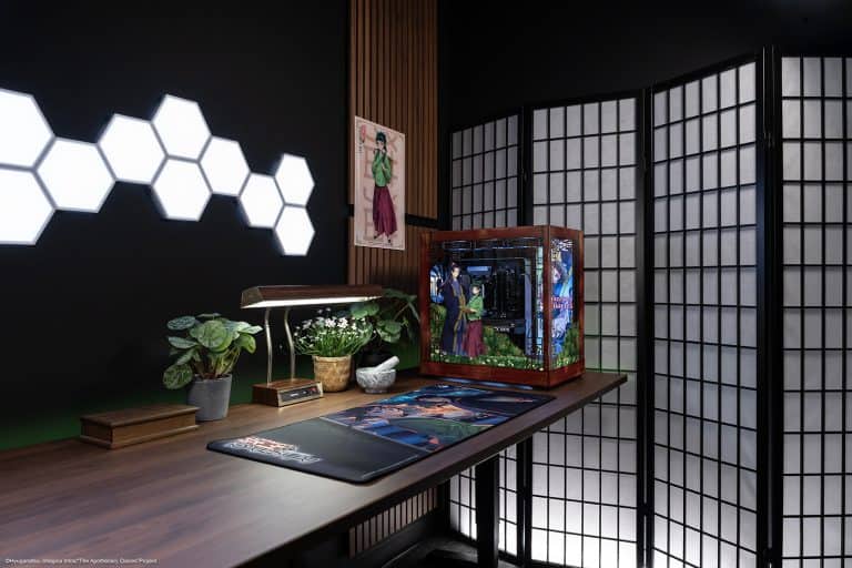 041326-Apothecary_Diaries-social-19 | The Outerhaven A decorated computer case on a wooden desk beside a desk lamp, potted plants, and a poster, set against a dark wall with hexagon lights and a folding shoji screen.