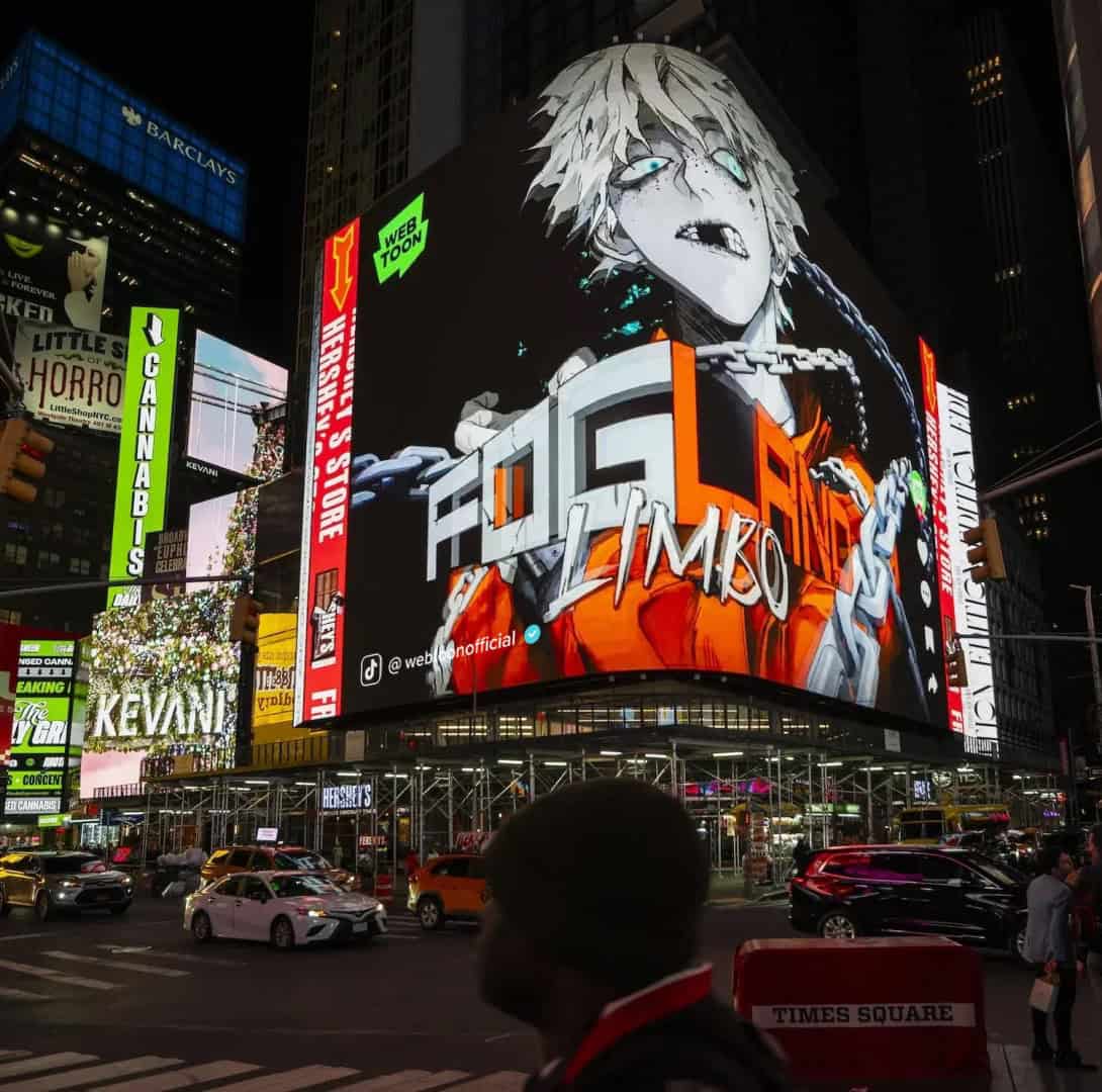 FOG LAND Times Square_2 | The Outerhaven Large illuminated billboard in Times Square displaying an anime-style character with bright orange and white graphics at night, with surrounding neon signs and traffic.