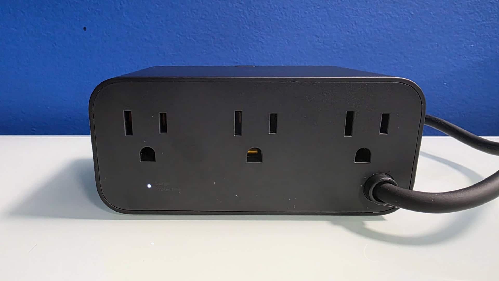 IMG_20260517_220732 | The Outerhaven Black five-outlet power strip with a cord plugged into the right, resting on a white surface, used to provide multiple outlets.