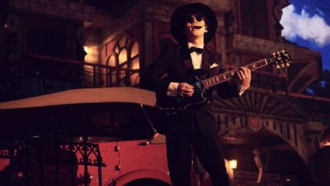 Nakajin-Sekai-No-Owari-Exclusive-Playlist-480x270 | The Outerhaven Musician in a black suit and hat plays an electric guitar beside a vintage red car on a dimly lit street set at night.
