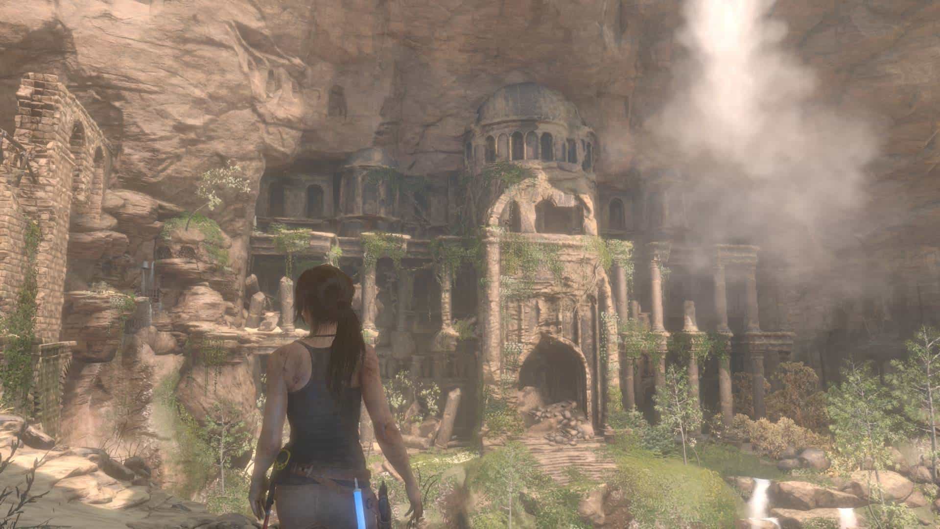 20260628214755-01KVNFMTMT35B9WX2451BXABJ3 | The Outerhaven Woman with dark hair in a tank top stands with her back to the camera, facing ancient ruins carved into a canyon with columns and a domed temple, shrouded in mist.