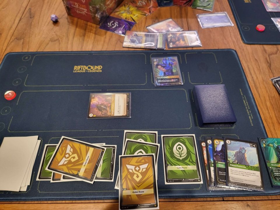 1000019614 | The Outerhaven Tabletop card game setup on a blue mat labeled Riftbound League of Legends, with cards in play and a deck on the right.