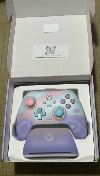 Gamesir Box Open | The Outerhaven Pastel Xbox controller with pink, blue, and purple camo design in white packaging with a matching lavender charging dock beneath it in a box