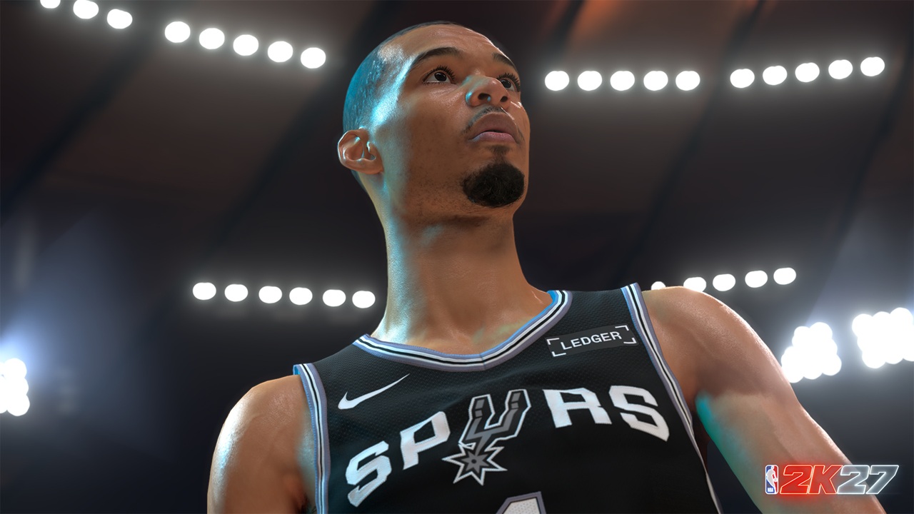 NBA 2K27 First Look Screenshots Victor Wembanyama 1 A close-up of a basketball player in a San Antonio Spurs jersey looking upward under arena lights, with the NBA 2K27 logo in the corner.