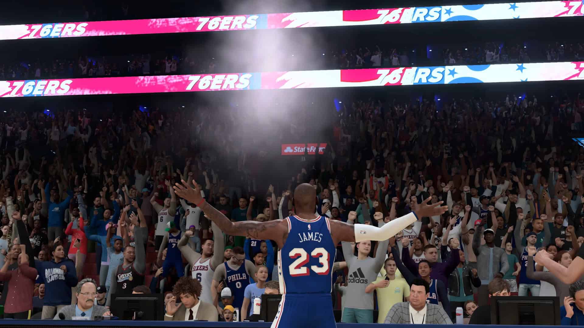 NBA 2K27_ Official Gameplay Trailer 0-26 screenshot Basketball player wearing a blue 23 James jersey faces a cheering packed arena with bright 76ers banners above.