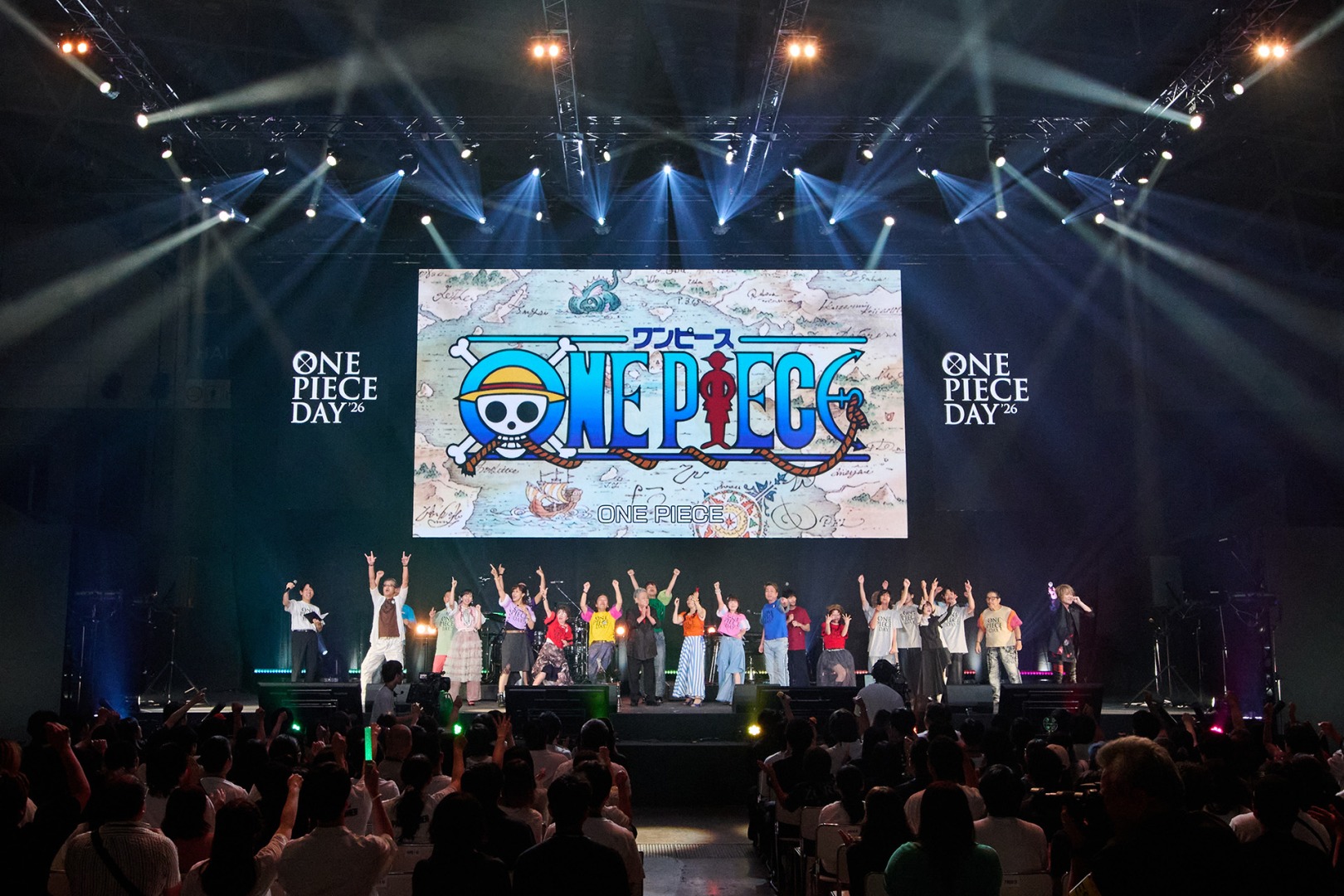 ONE PIECE | The Outerhaven Stage with a large One Piece display as performers raise their arms to the cheering crowd at One Piece Day 26 showDate on screen left and right panels.
