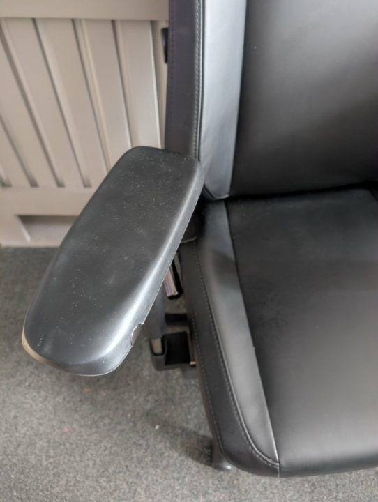 BAP Arms | The Outerhaven Close-up of a black leather office chair seat with a padded armrest on the side viewed from the side.