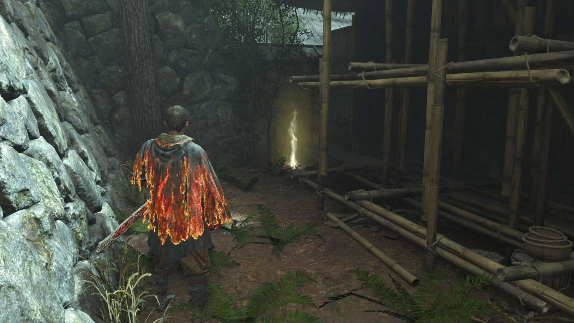 Onimusha Item | The Outerhaven Back view of a person in a burning orange cloak with a red sword, standing in a rocky cave with bamboo scaffolding nearby.
