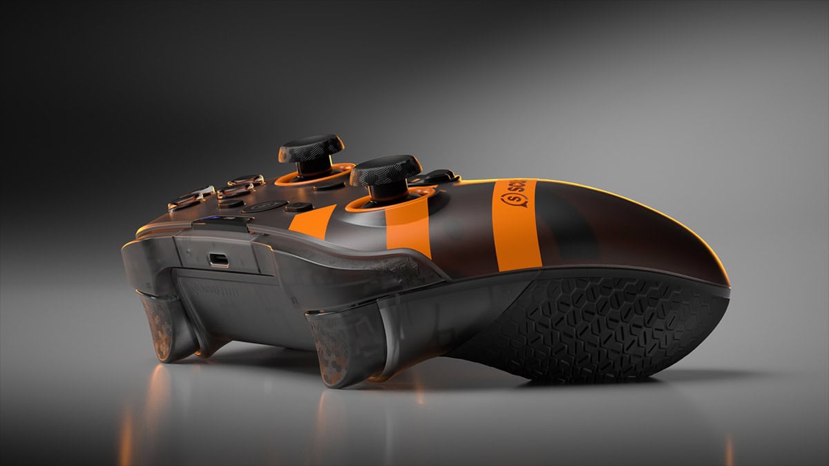 SCUF26-Nemesis-GTM-PK-2 1 | The Outerhaven Low-angle shot of a black and orange game controller with textured grips and orange stripes, resting on a reflective surface.