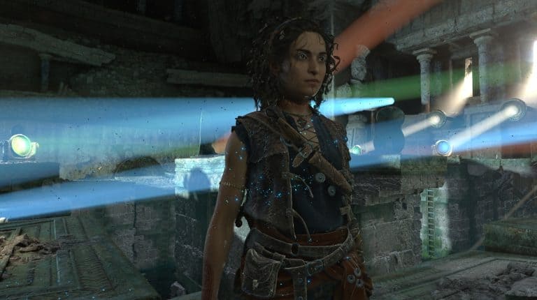 Female warrior in brown leather armor stands in ruined stone temple, light beams cutting through the dust around her.